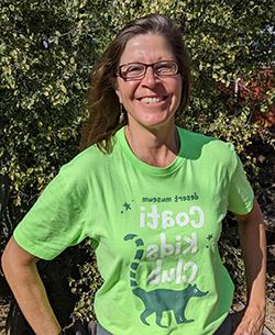 Robin stands in front of a green-leaved bush, wearing a Museum t-shirt